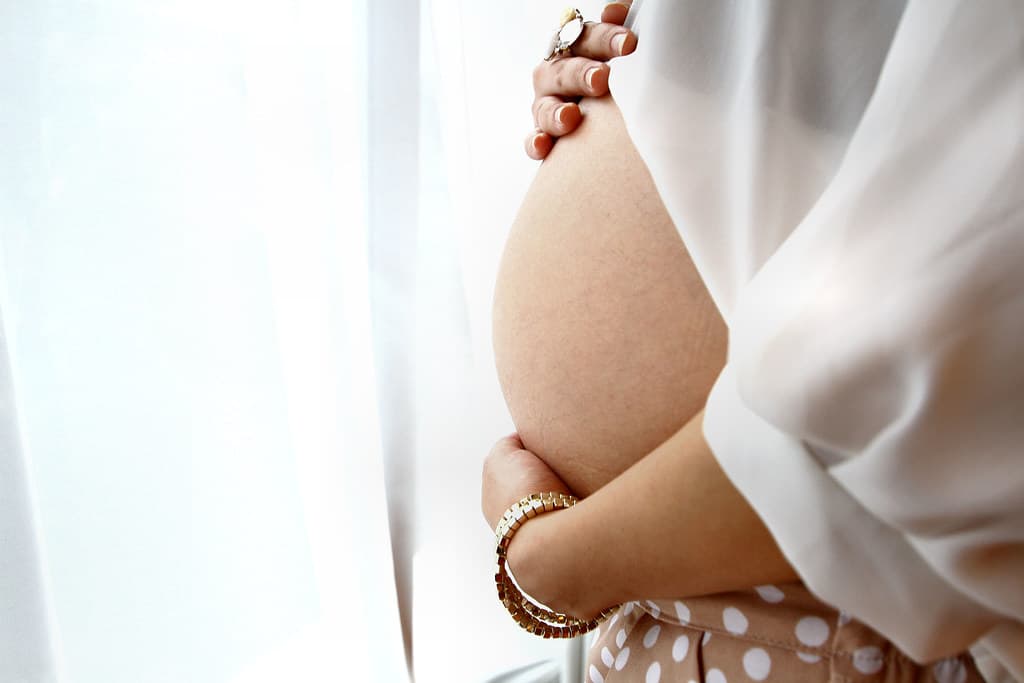 An expecting mother cradling her belly, the kind of moment Family Voices is built to keep